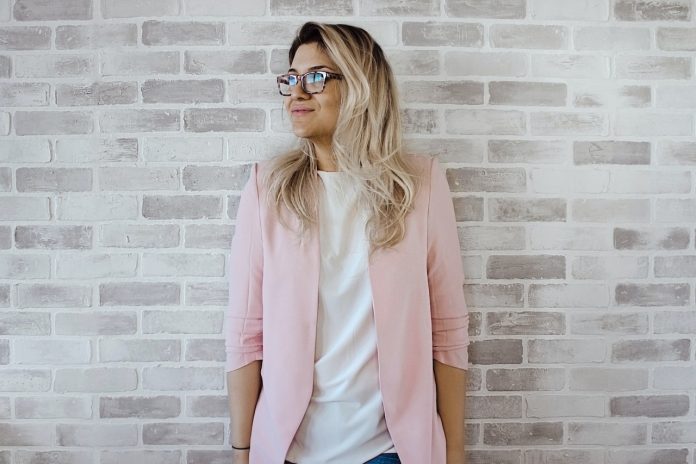 woman-in-pink-cardigan-and-white-shirt-leaning-on-the-wall